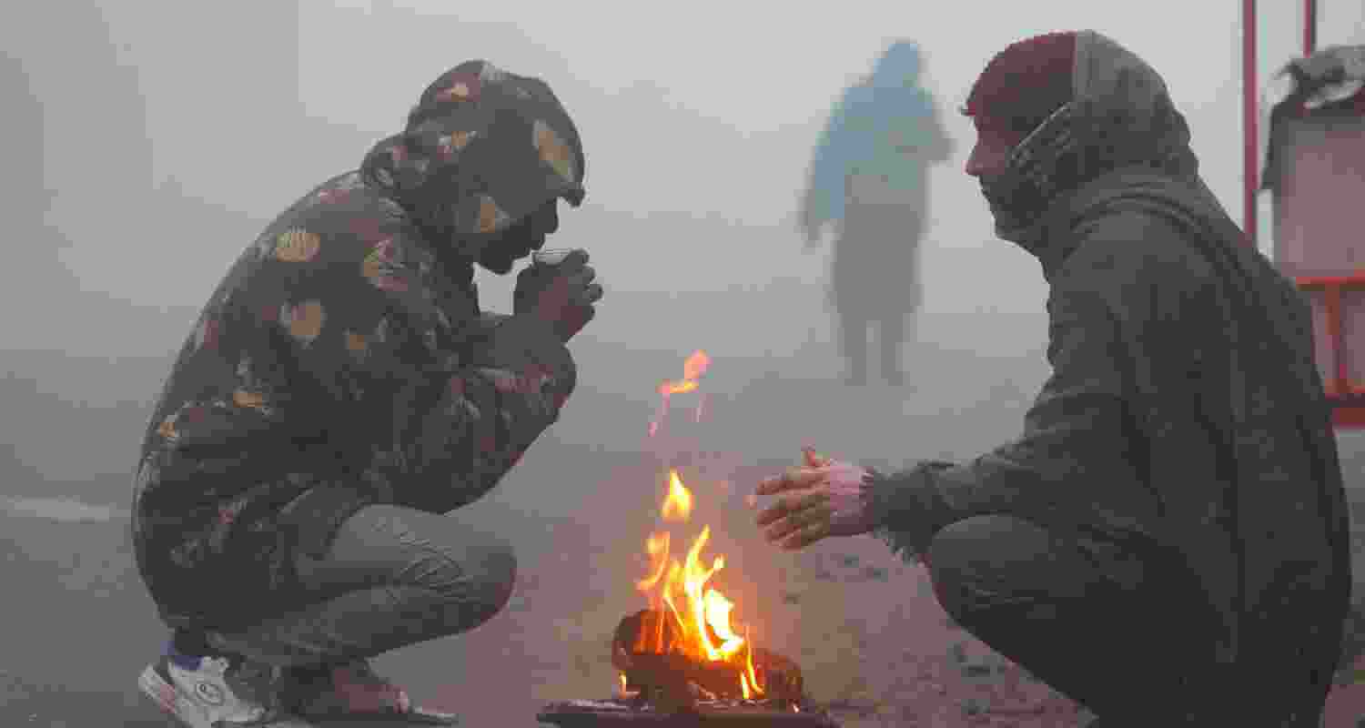 People warm themselves around a bonfire on a foggy winter morning, in Jammu, Tuesday. 