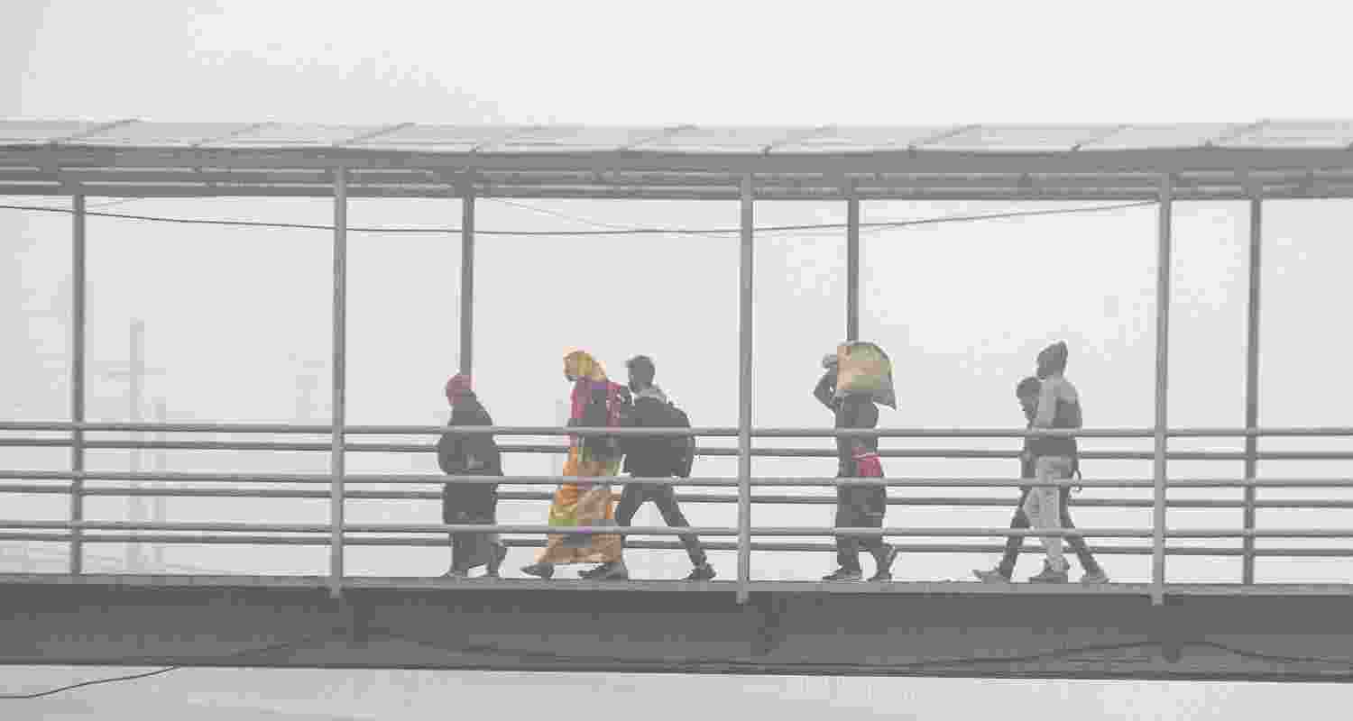 Commuters walk across a foot over bridge on a smoggy winter morning, in New Delhi.