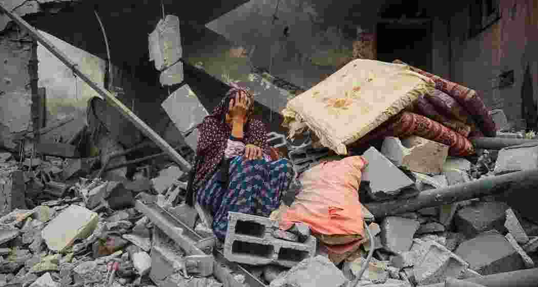 A Palestinian woman sits on the rubble of her house, destroyed in an Israeli strike, in the Nuseirat refugee camp in central Gaza.