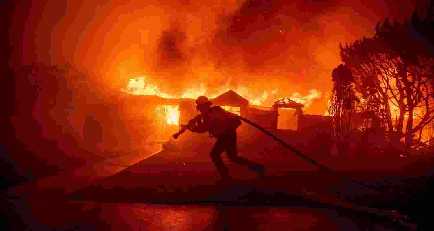 A firefighter carries a hose during the palisades fire, Los Angeles.
