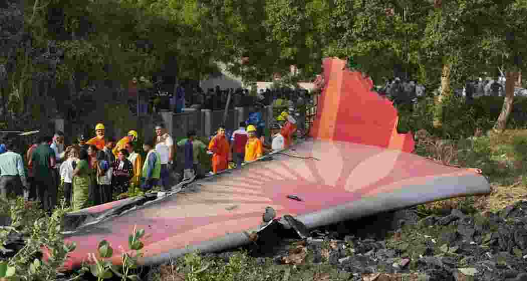 Security personnel, disaster management teams and locals near a wing section at the Ahmedabad crash site.