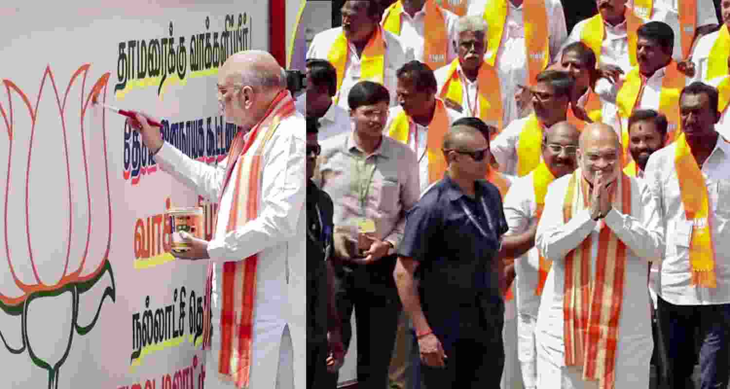 Union Home Minister Amit Shah paints BJP's logo on wall during a public meeting, in Karaikal, Puducherry, Saturday. 