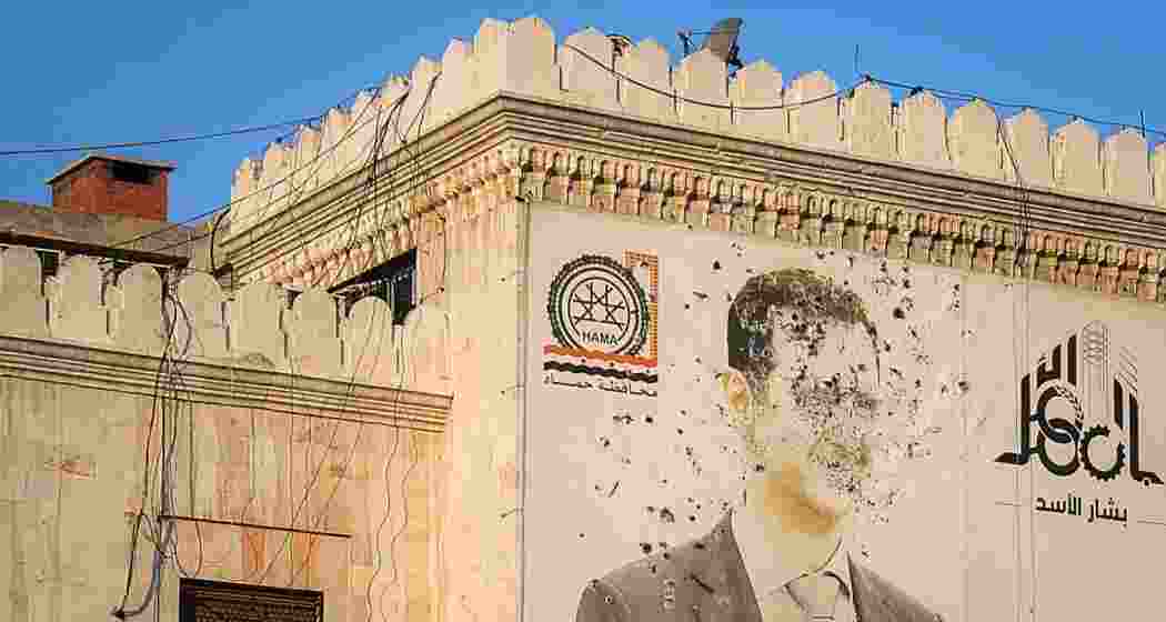 An image of Syrian President Bashar al-Assad, riddled with bullets, is displayed on the facade of the provincial government office following the opposition's capture of Hama.