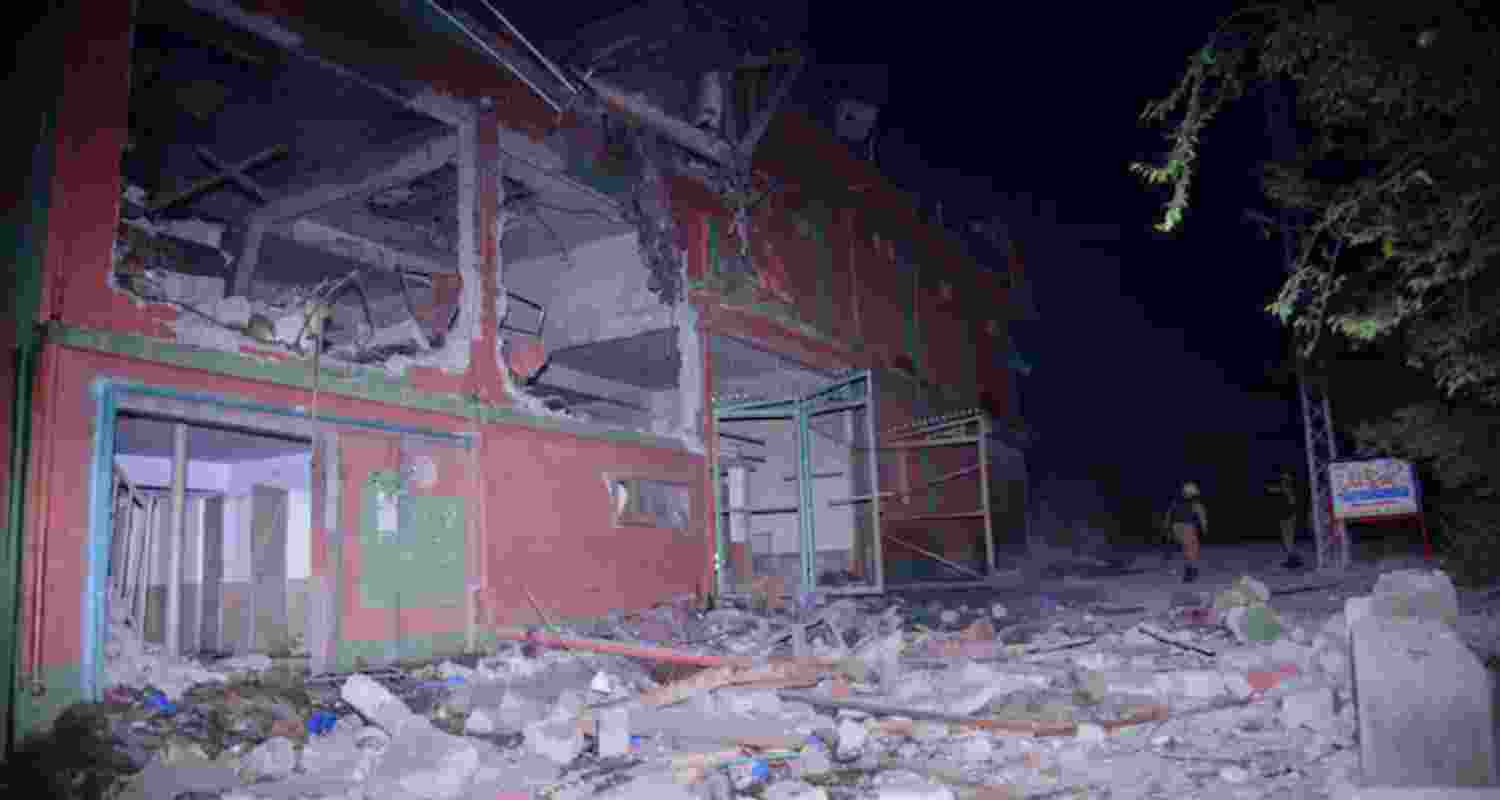 Local residents and members of media examine a building damaged by a missile strike near Muzaffarabad in Pakistan-controlled Kashmir.