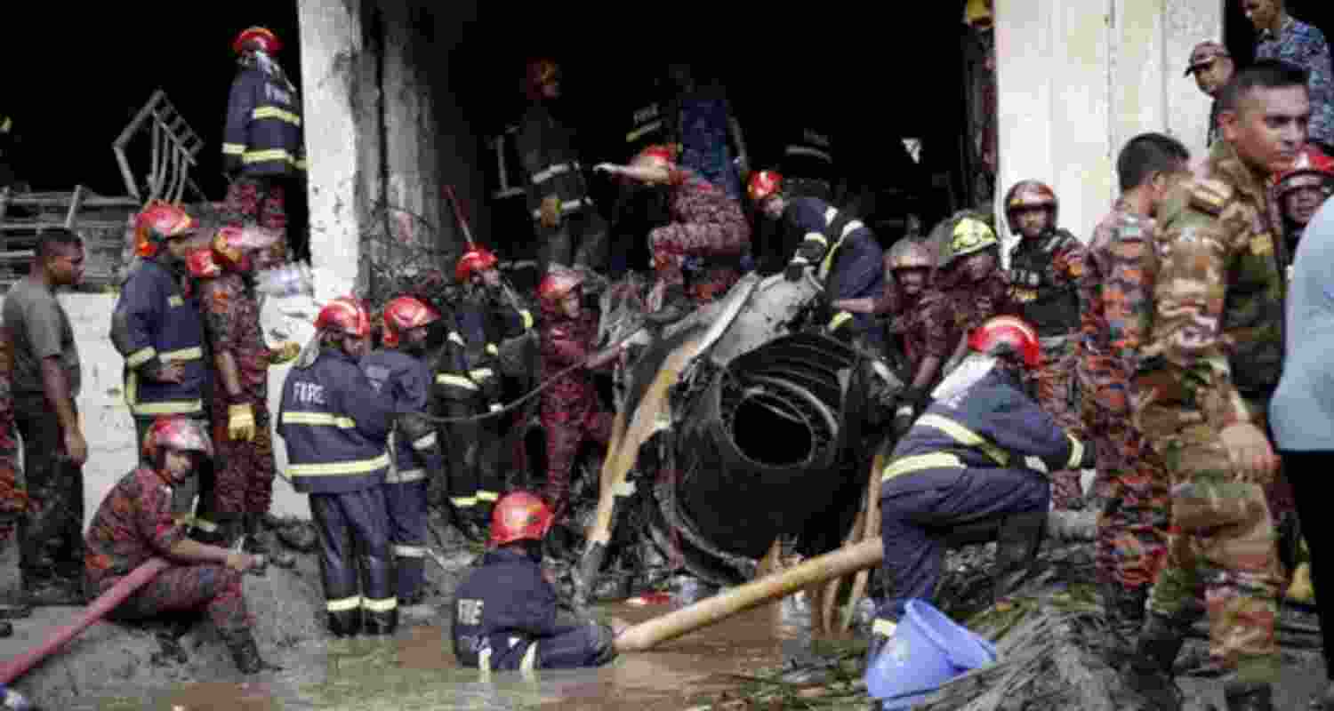 Firefighters work to remove the wreckage from a building, after an air force training aircraft crashed into Milestone College campus, in Dhaka, Bangladesh.