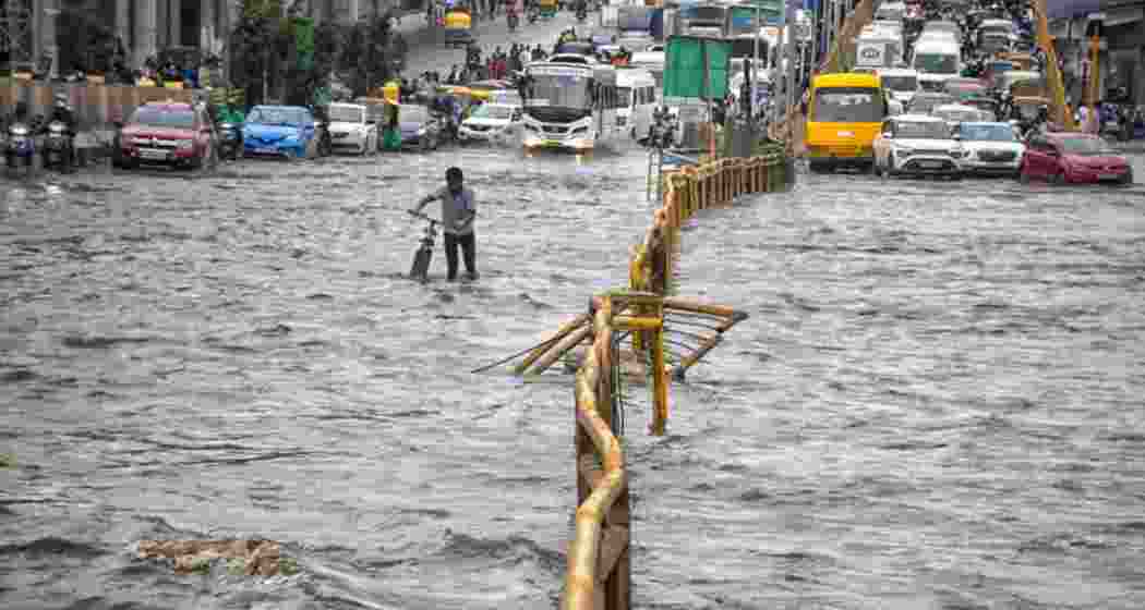 Commuters wade through a waterlogged road after heavy rains, in Bengaluru, Tuesday.
