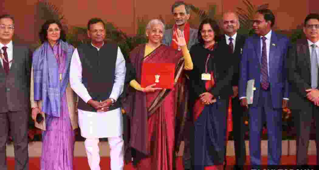 India's Finance Minister Nirmala Sitharaman waves as she holds a folder bearing the Government of India's emblem, while posing with her officials before leaving her office to present the annual federal budget in parliament, in New Delhi, India on Sunday.
