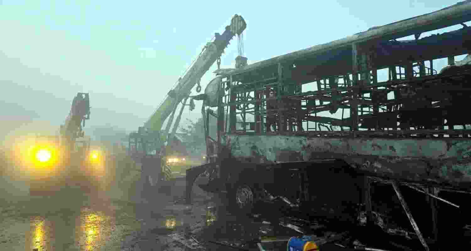 Cranes clear the charred remains of buses after a fog-hit pile-up involving several buses and cars triggered fires on the Yamuna Expressway, in Mathura, Tuesday.