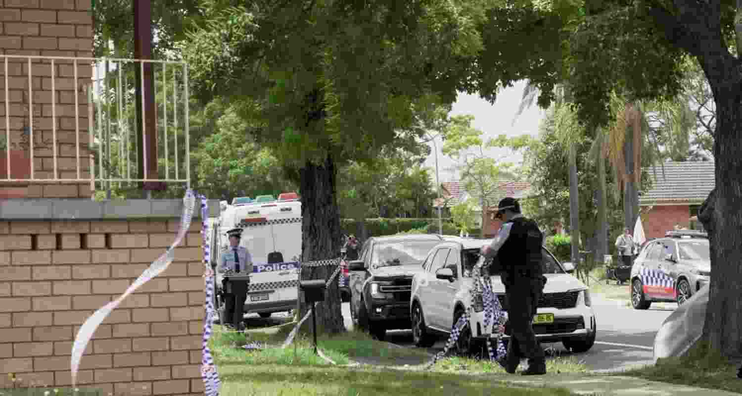 A police officer removes police tape from outside the house of the suspects of a shooting incident on a Jewish holiday celebration at Bondi Beach, in Bonnyrigg, Sydney.