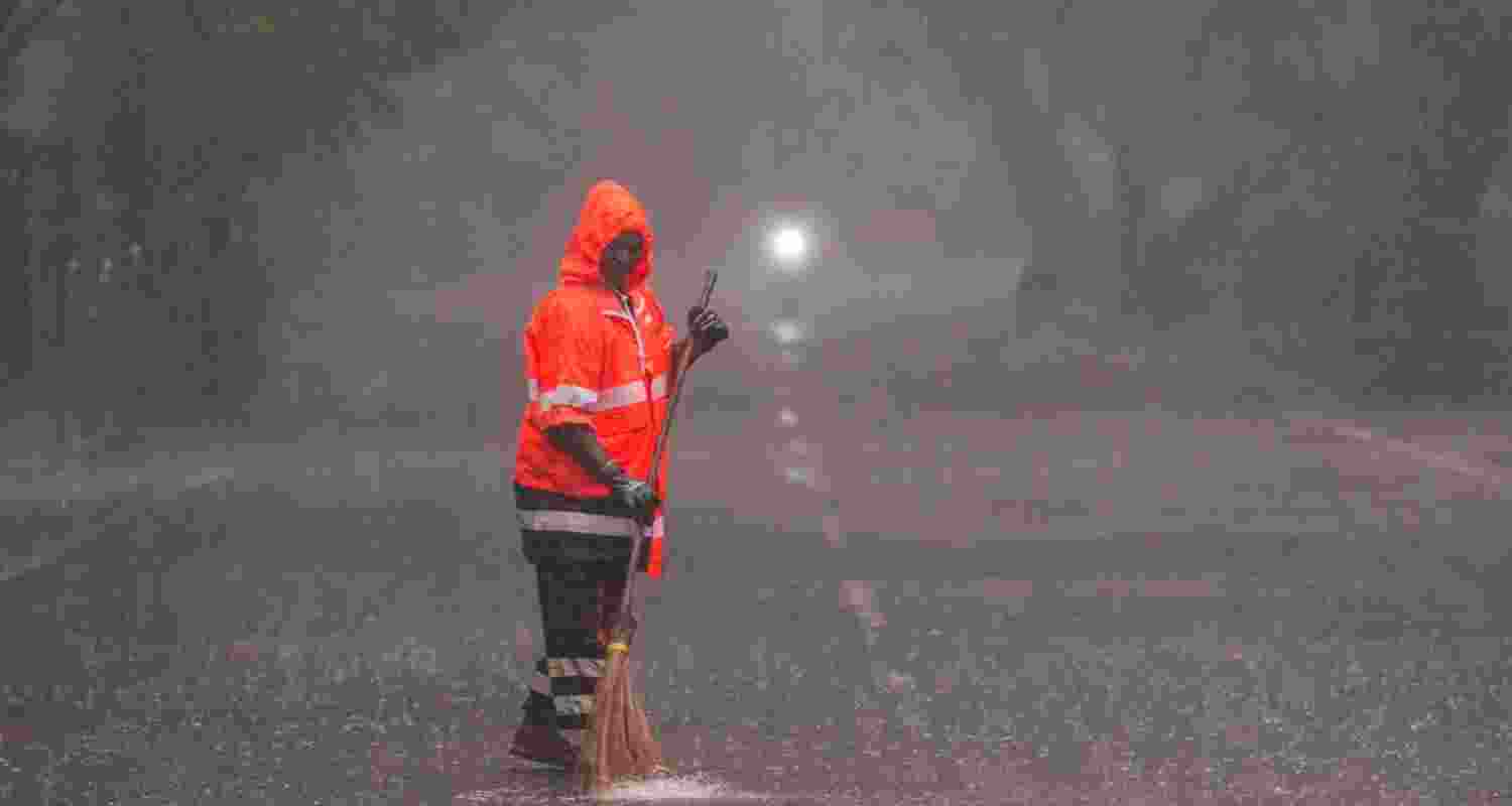 A sanitation worker cleans a street in Chennai while torrential rains fall across the state, on Thursday.