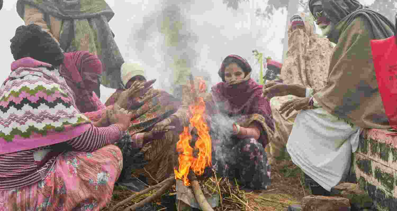 People warm themselves around a bonfire on a foggy winter morning, on the outskirts of Amritsar. 