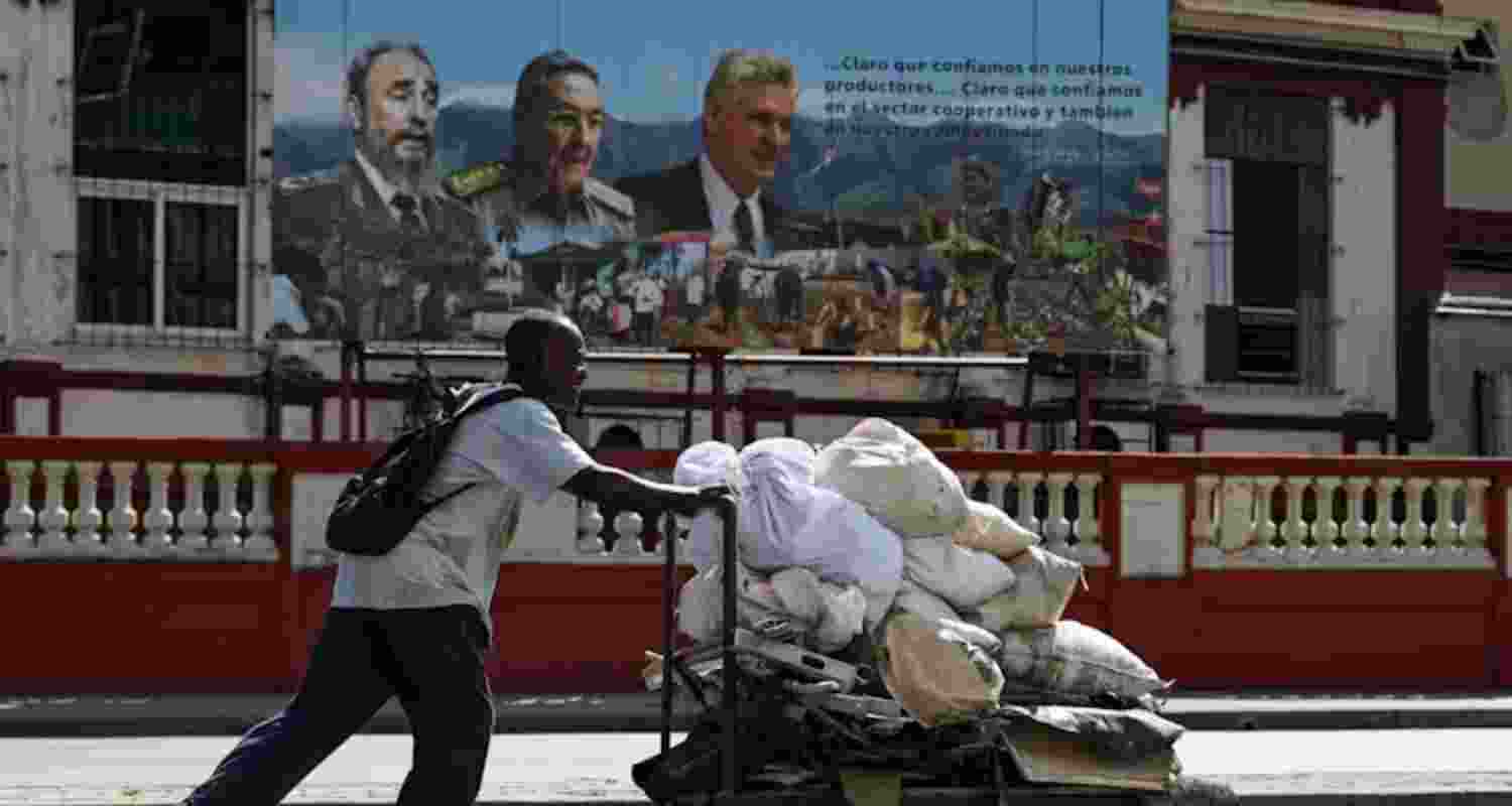 A man pushes a cart against a backdrop of former Cuban leaders.