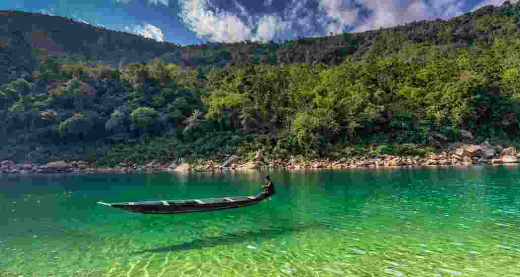 A boatman guides his wooden craft along the transparent waters of the Umngot River in Dawki, Meghalaya.