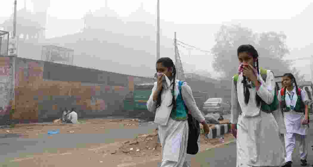 Schoolchildren cover their faces while walking to school amid dense smog in New Delhi. Image: Getty Images.