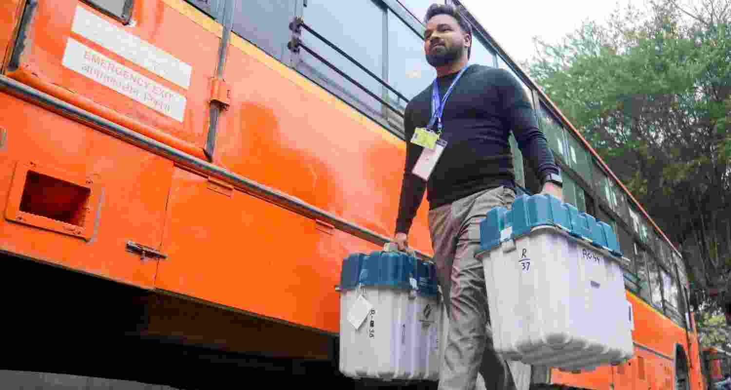 A polling officials carrying EVMs and other election materials arrives at a polling centre at Gole Market ahead of Delhi Assembly poll, in New Delhi, Tuesday