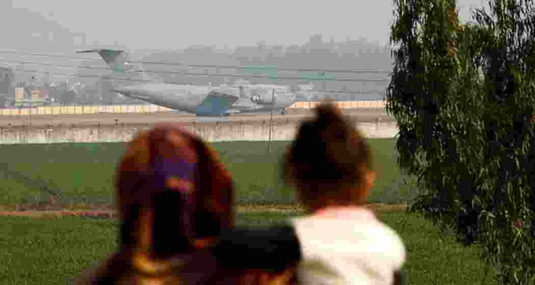 Onlookers watch as a US military plane carrying deported Indian immigrants lands in Amritsar.