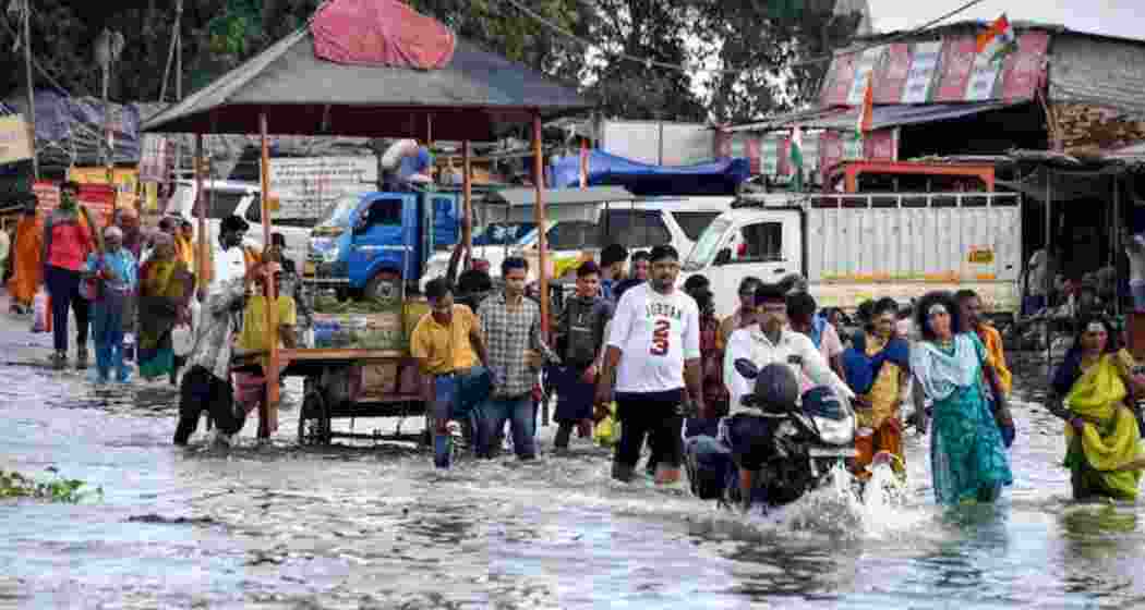 People wade through knee-deep water in a flood-affected locality in Prayagraj on Thursday as the Ganga and Yamuna continue to swell following heavy monsoon rainfall.