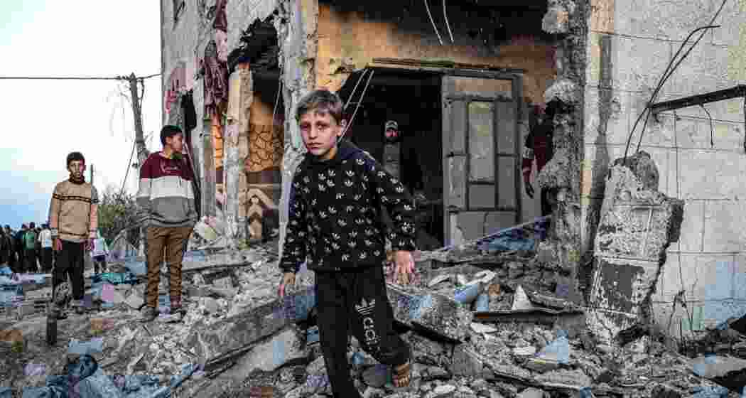 People walk through the rubble of a building heavily bombed by Israeli forces in Rafah, Gaza.
