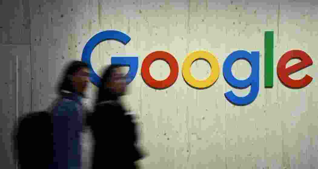 People walk along a Google logo. 