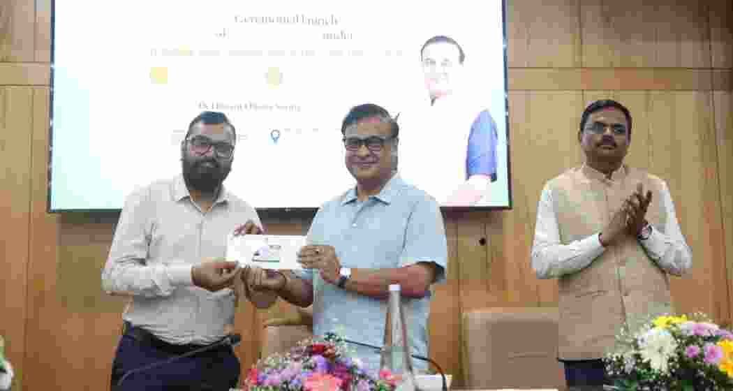 Assam Chief Minister Himanta Biswa Sarma hands over cashless medical facility papers to a government employee and pensioners under the Ayushman Asom Mukhya Mantri Lok Sevak Arogya Yojana in Guwahati.