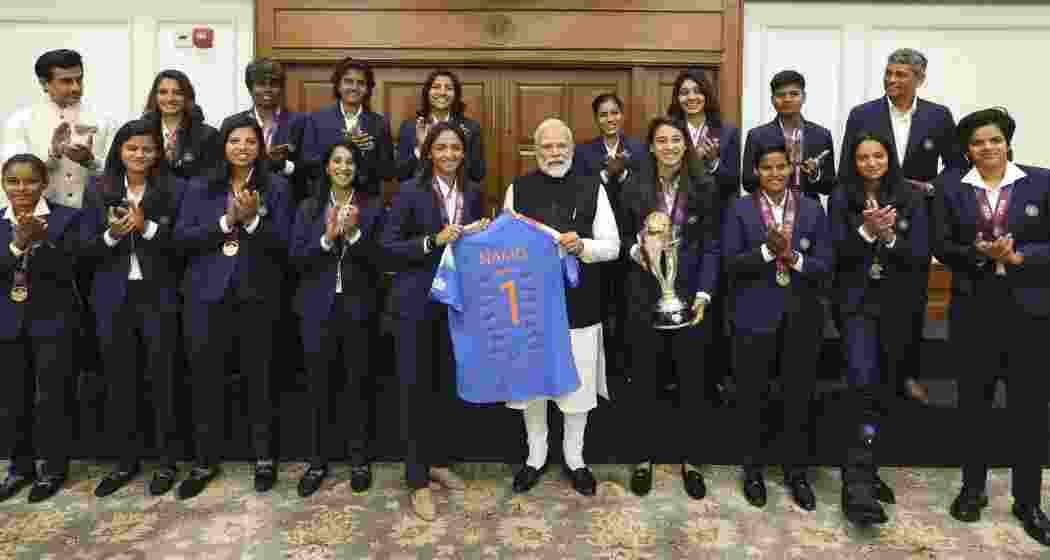 Prime Minister Narendra Modi holds a jersey with captain Harmanpreet Kaur as he poses for a photograph with the Indian women's cricket team, in New Delhi on Wednesday.