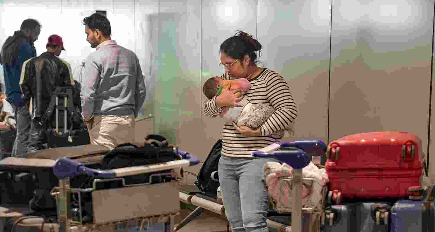 A passenger looks after a newborn baby as she waits at Terminal 1 (T1) of the Indira Gandhi International Airport, in New Delhi, Saturday, Dec. 6, 2025. Domestic carrier IndiGo has cancelled over 200 flights from Delhi and Mumbai on Saturday, a day after managing to temporarily secure major relaxations in the second phase of the court-mandated new flight duty and rest period norms for cockpit crew, sources said. 