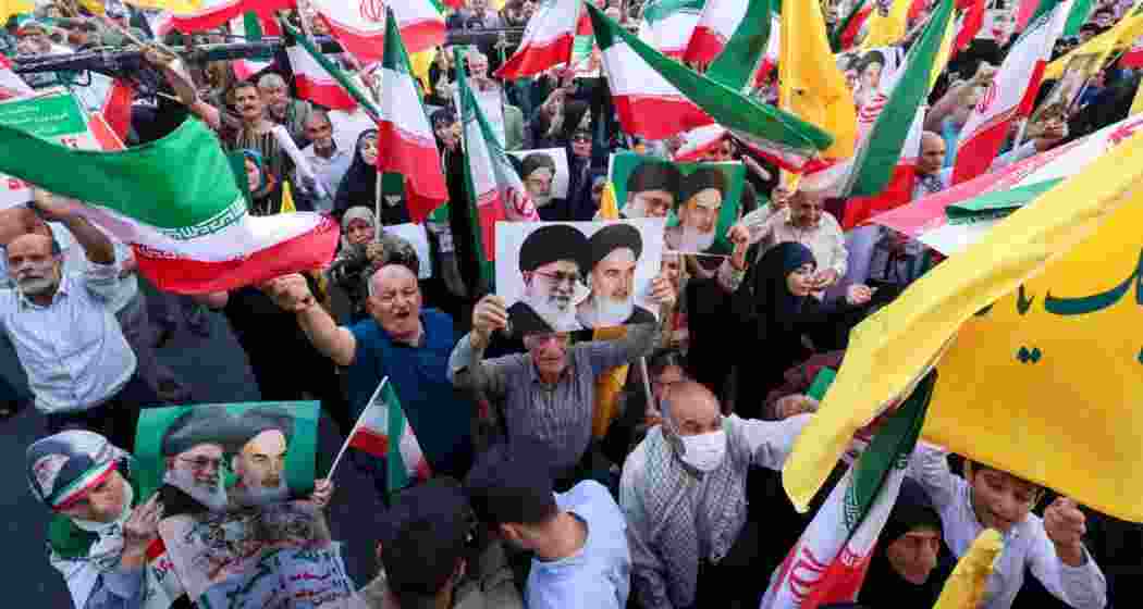 Iranians chant slogans, wave national flags, and hold portraits of Iranian supreme leader Ayatollah Ali Khamenei and late supreme leader Ayatollah Ruhollah Khomeini, as they celebrate a ceasefire between Iran and Israel at Enghlab Square in the capital Tehran on June 24, 2025.