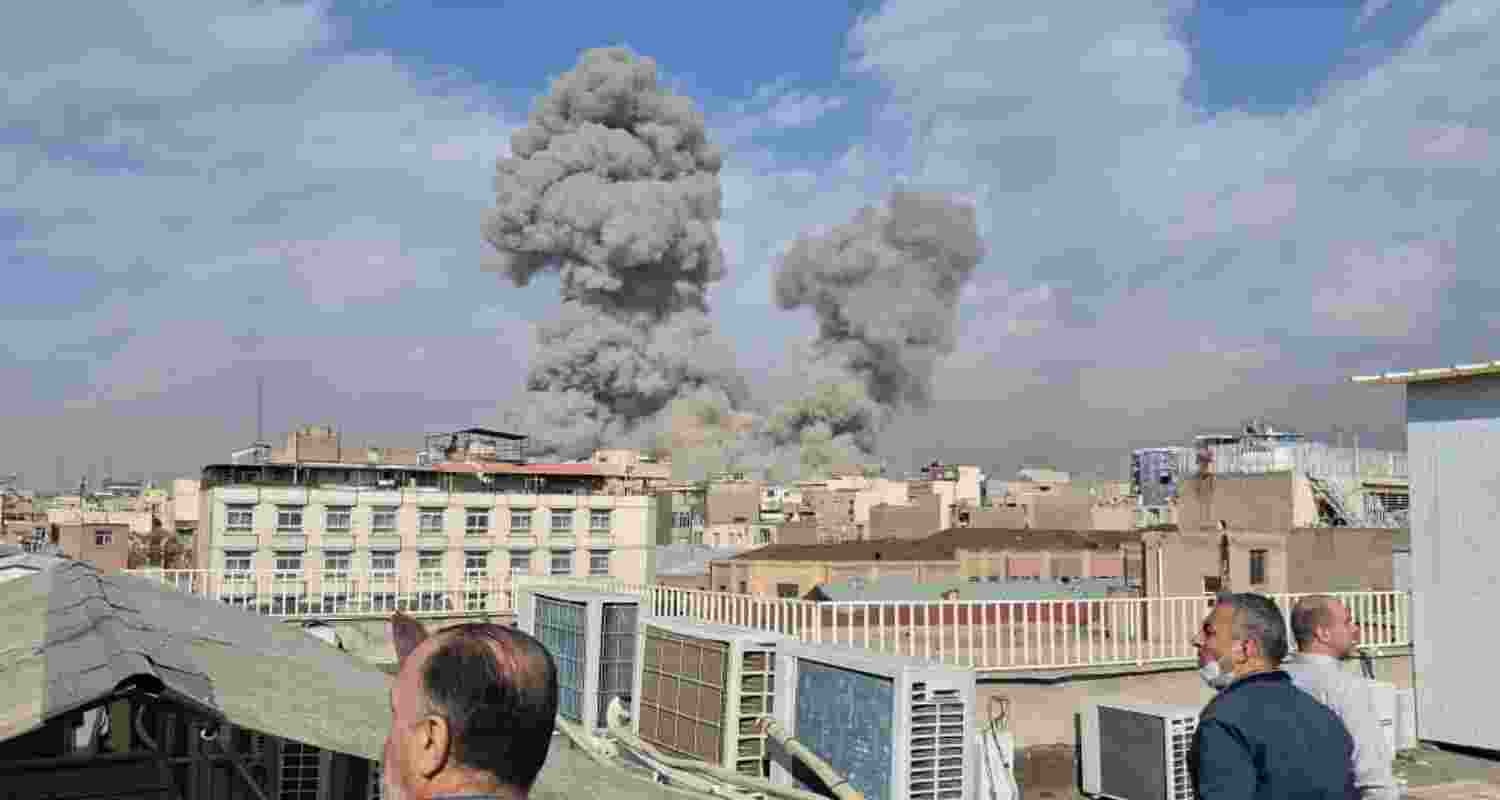 People watch as smoke rises on the skyline after an explosion in Tehran, Iran, Saturday. 