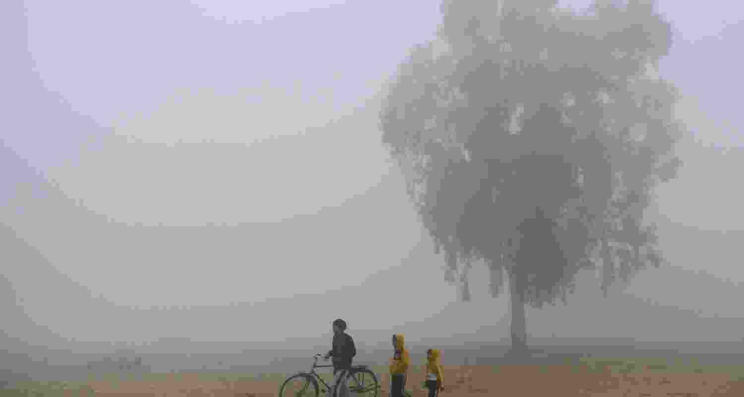  A man and children brave a foggy winter morning, in Jalandhar, Punjab, Saturday. 
