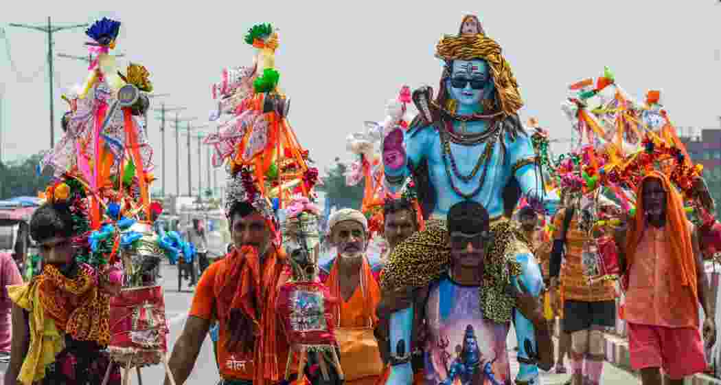 Kanwariyas, devotees of Lord Shiva, walk along a road during the annual Kanwar Yatra in the holy month of Shravan, in New Delhi, Tuesday.