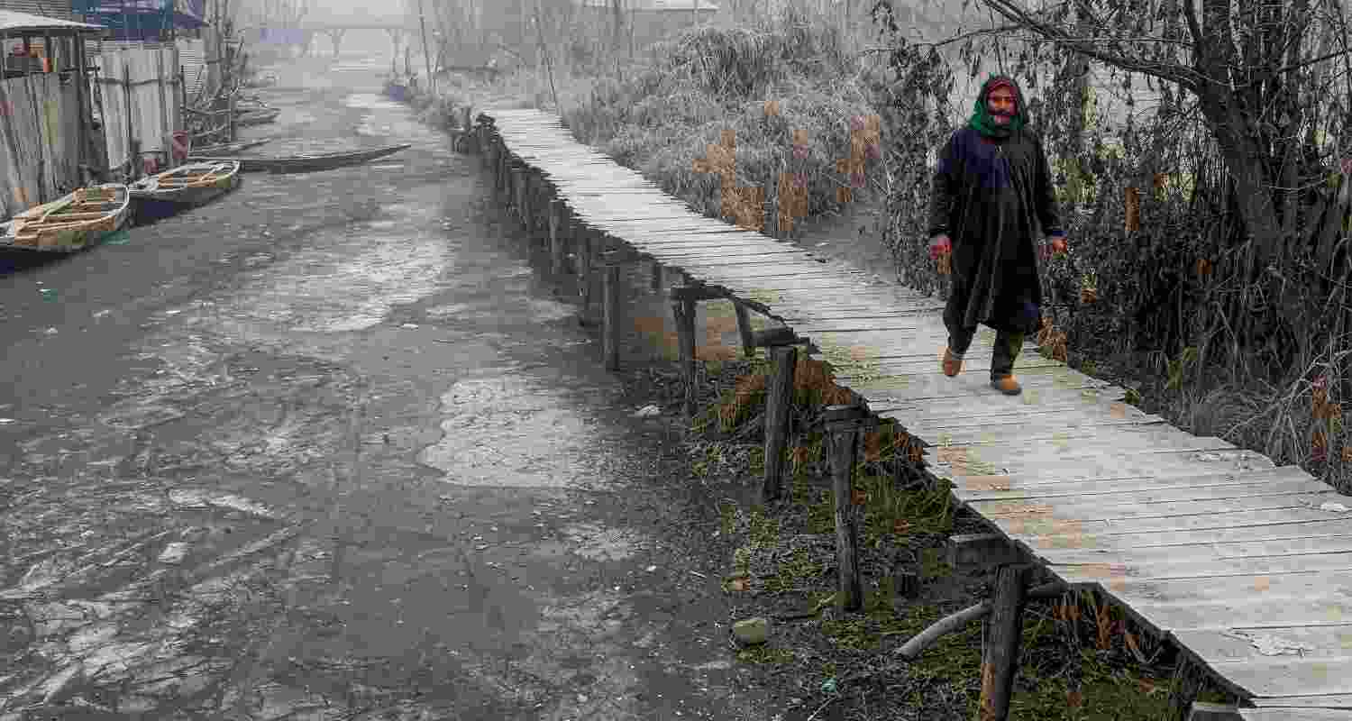  A man walks on a wooden bridge at partially frozen interior Dal Lake during a cold winter morning, in Srinagar, Friday, Dec. 27, 2024. As cold wave intensifies in Kashmir Valley, temperature dropped several degrees below zero, with Srinagar recording the minimum temperature at minus 7.3 degrees Celsius. 