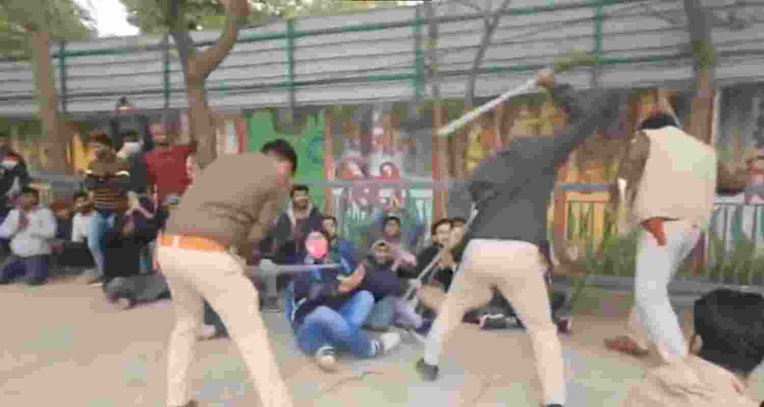 Police personnel lathi-charge protestors in Patna.