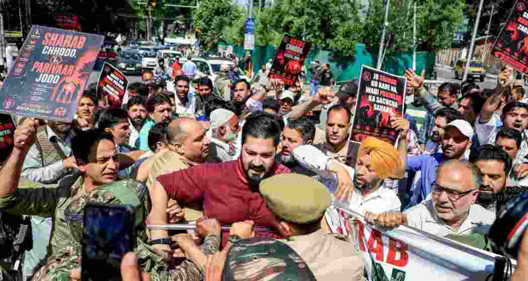 Police and security personnel try to stop BJP leaders and workers as they stage a protest over the demand to ban liquor, in Srinagar.