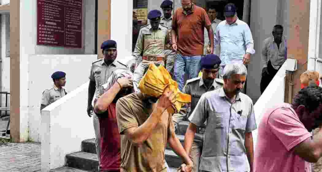 Security personnel escort accused as they come out of a Delhi court after a hearing in the alleged NEET-UG 2026 paper leak case in New Delhi on Monday.