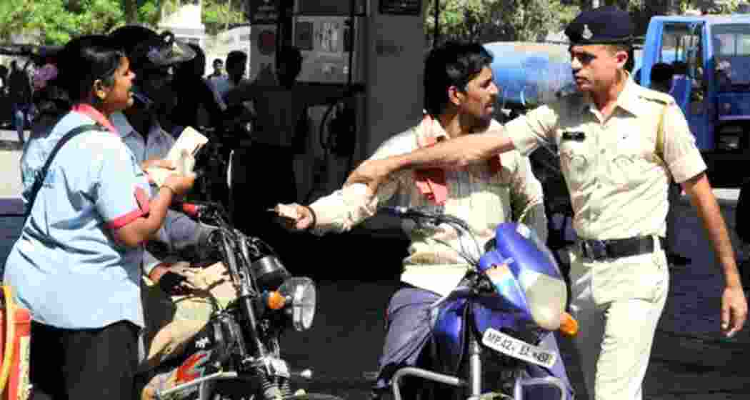 A police officer stops a helmetless rider from paying at a fuel station.