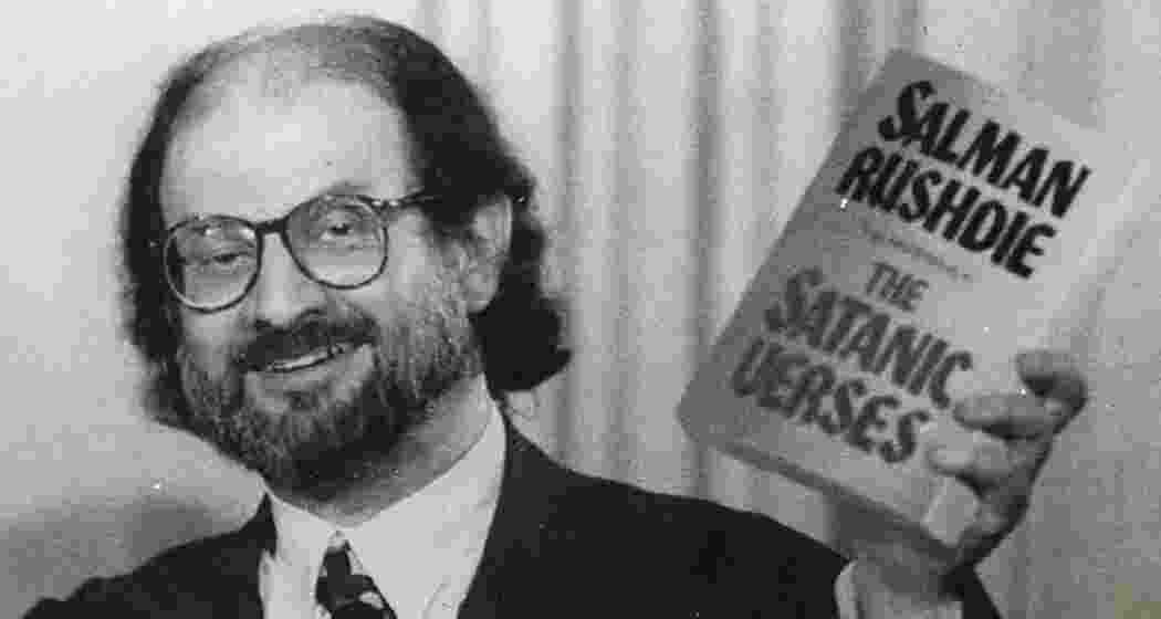 Salman Rushdie holds a copy of the newly-published paperback version of his controversial novel “The Satatanic Verses”, during a speech in Arlington, Virginia on March 24, 1992. India was one of the first countries to ban the book’s import and sale, citing concerns over its content being offensive to the Muslim community