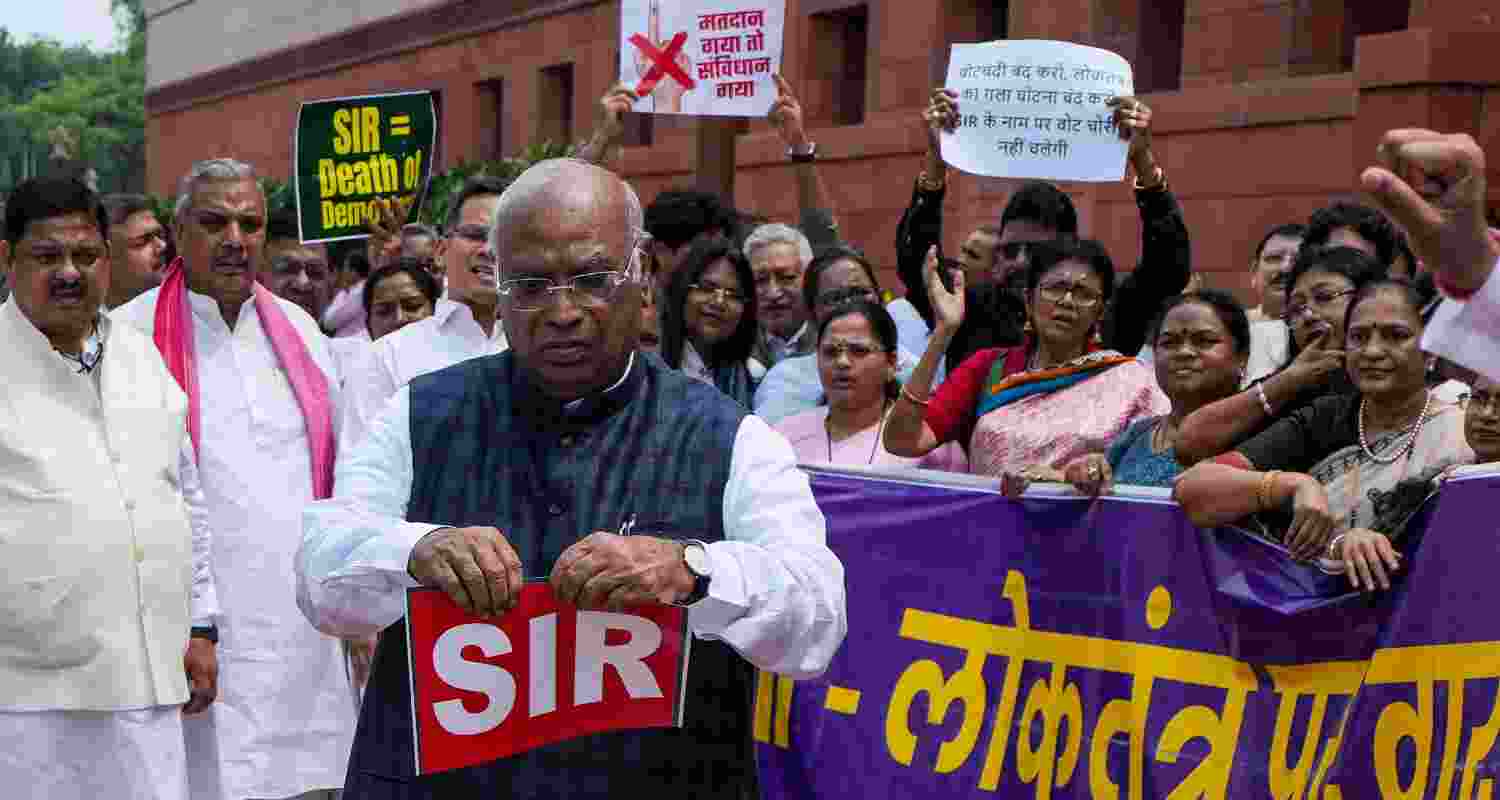 Leader of Opposition in Rajya Sabha and Congress MP Mallikarjun Kharge tears a placard, written SIR on it and dumps it in a dustbin during the Opposition's protest over the Special Intensive Revision (SIR) of Electoral Rolls in Bihar, during the Monsoon session of Parliament, in New Delhi, Friday.