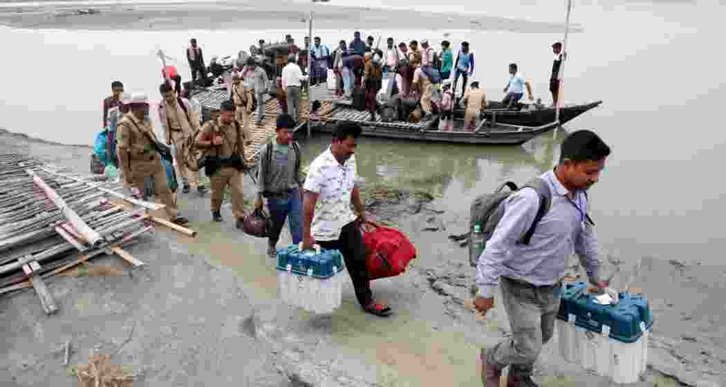 Polling officials carry election materials after disembarking from a boat as they head to a remote polling station ahead of the first phase of India's general election in the Majuli district, in the northeastern state of Assam, India.