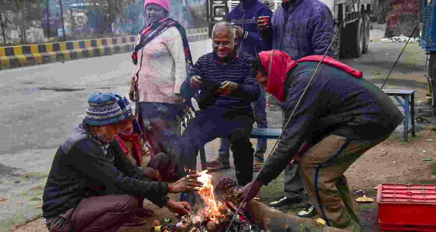 People sit around a bonfire to keep themselves warm on a winter morning, in Prayagraj, Saturday. 