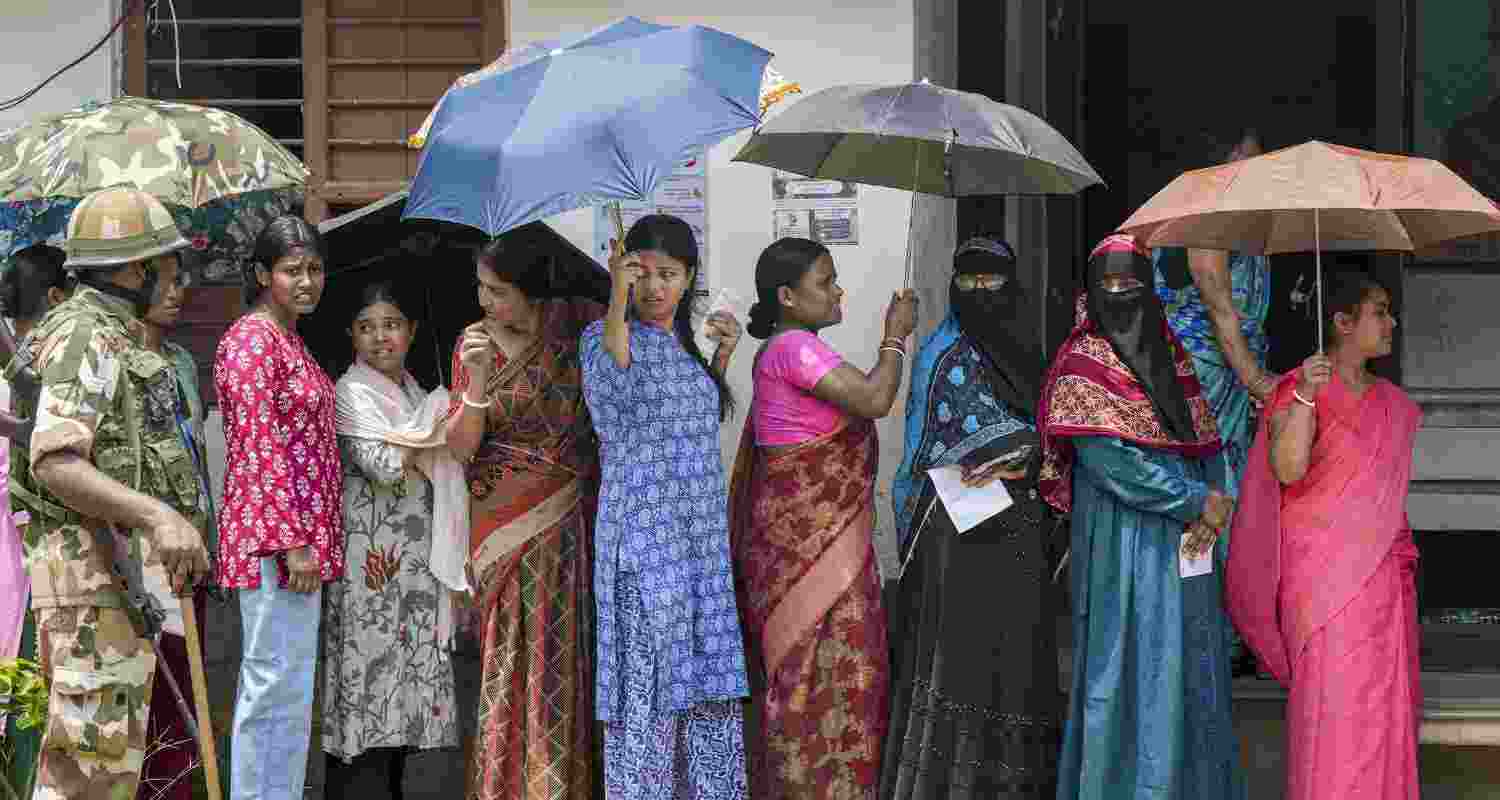  People take shade while waiting in a queue before voting in the first phase of the West Bengal Assembly elections, at a polling station in Panskura, Purba Medinipur, Thursday, April 23, 2026.