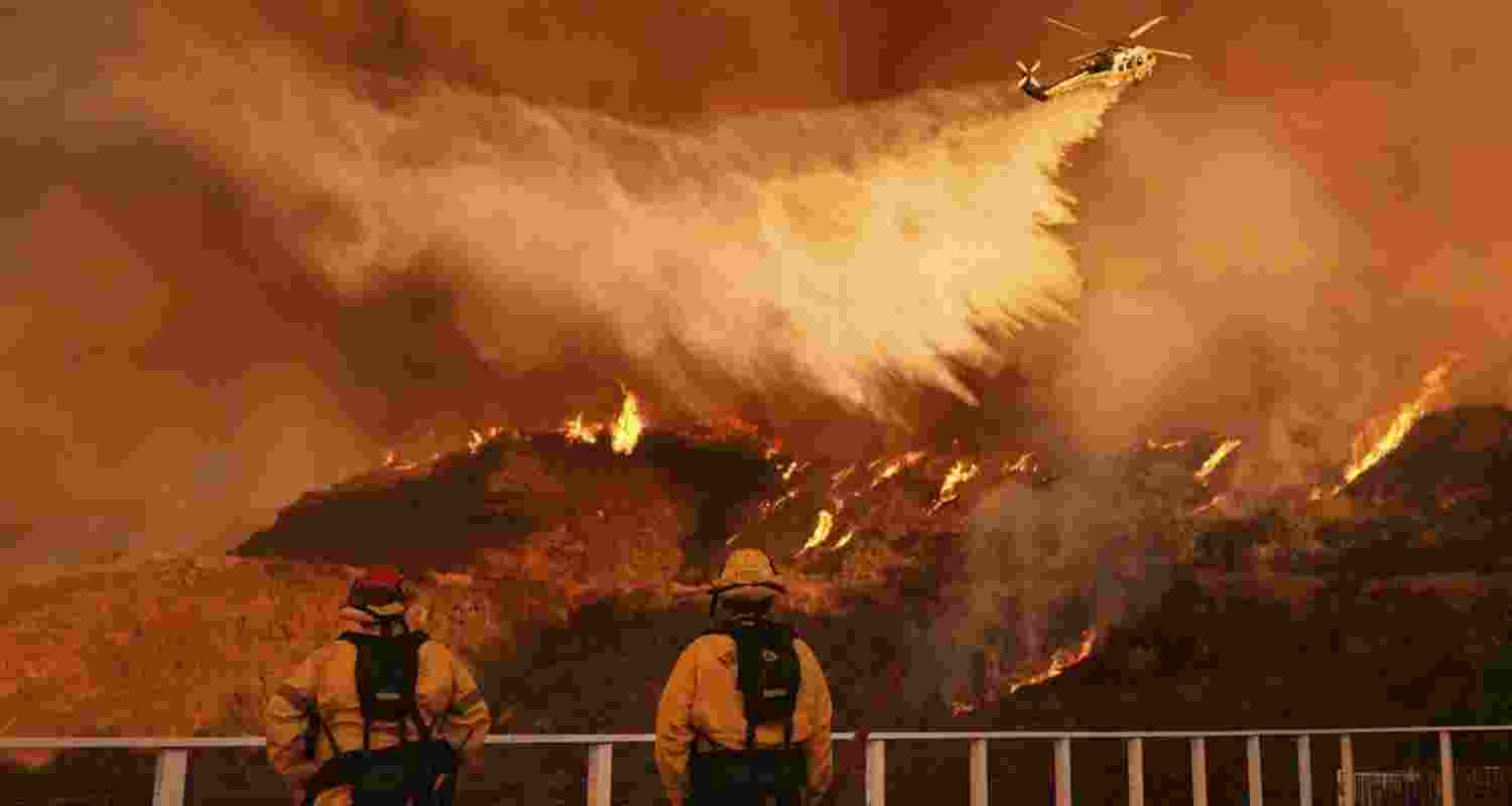 Firefighters watch as water is dropped on the Palisades Fire in Mandeville Canyon on Monday.