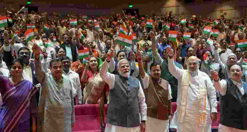 Prime Minister Narendra Modi waving towards NDA MPs holding the national flag after they greeted him in the Parliament Library ahead of the weekly parliamentary party meeting.