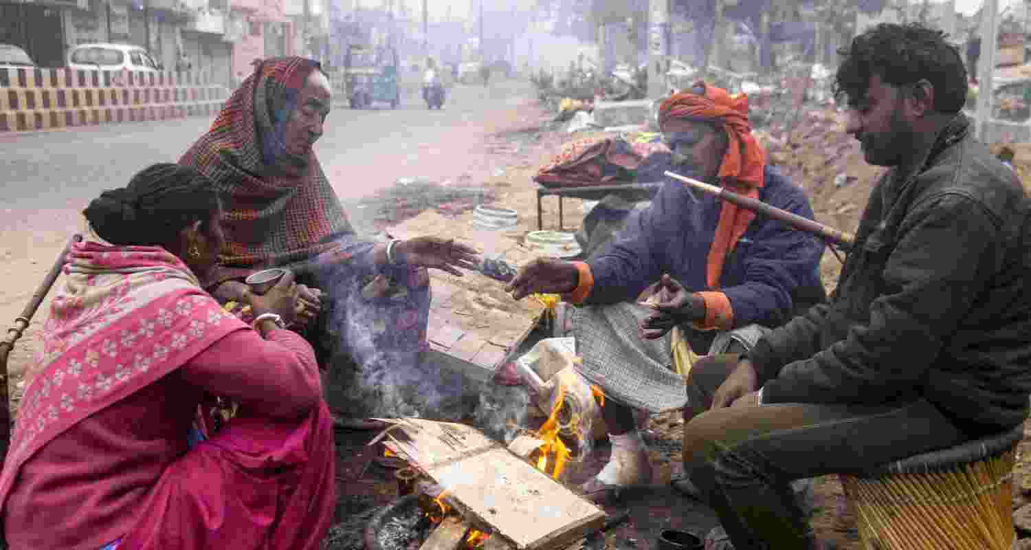 People sit around a bonfire on a cold winter morning, in Gurugram, Sunday. People sit around a bonfire on a cold winter morning, in Gurugram, Sunday.
