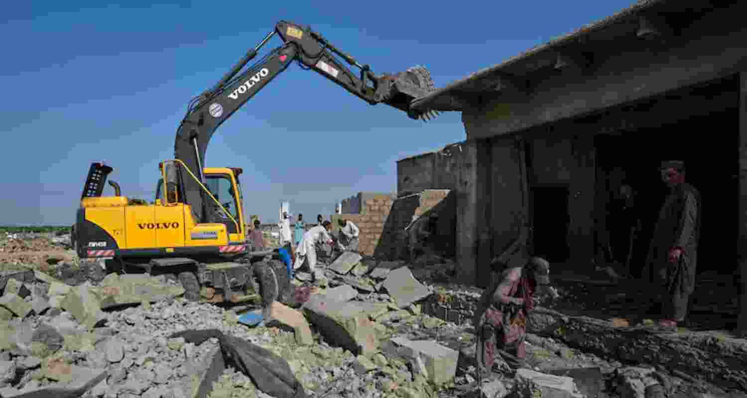 A hydraulic shovel demolish a structure during an operation against illegal settlement of Afghan refugees conducted by local government, on the outskirts of Karachi, Pakistan, Wednesday. A hydraulic shovel demolish a structure during an operation against illegal settlement of Afghan refugees conducted by local government, on the outskirts of Karachi, Pakistan, Wednesday.