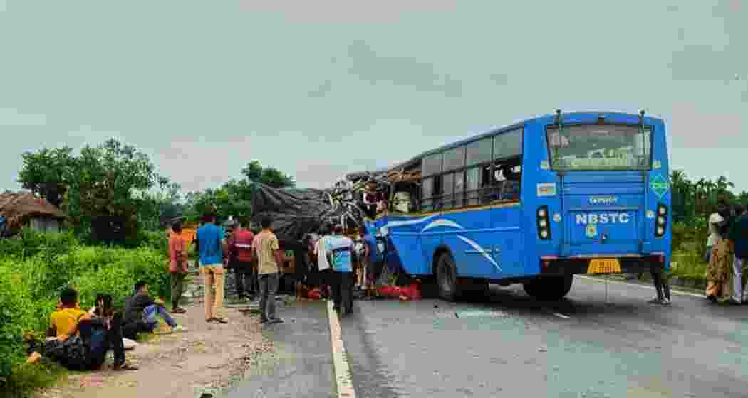 Local residents gather around the damaged NBSTC bus after it rammed into a stationary trailer on NH-27 in Jalpaiguri district on Sunday, while injured passengers await assistance by the roadside. Local residents gather around the damaged NBSTC bus after it rammed into a stationary trailer on NH-27 in Jalpaiguri district on Sunday, while injured passengers await assistance by the roadside.