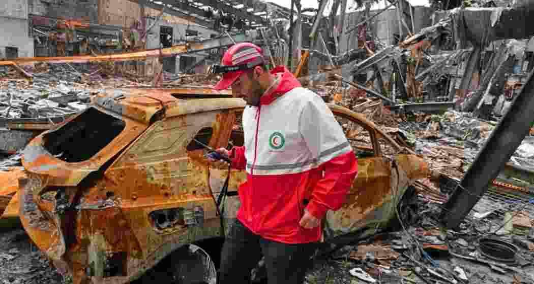A member of the Iranian Red Crescent Society walks at Hypercar, an auto service center, amid damages which according to the company's officials was caused by strikes. A member of the Iranian Red Crescent Society walks at Hypercar, an auto service center, amid damages which according to the company's officials was caused by strikes.