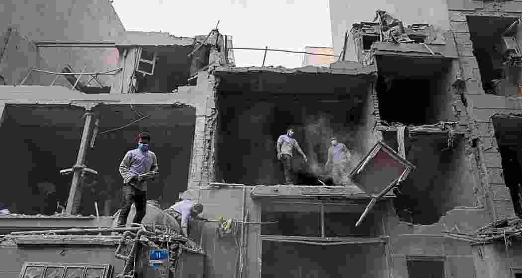 Volunteers clean debris from a residential building damaged when a nearby police station was hit Friday in a U.S.-Israeli strike in Tehran, Iran, on Sunday. Volunteers clean debris from a residential building damaged when a nearby police station was hit Friday in a U.S.-Israeli strike in Tehran, Iran, on Sunday.