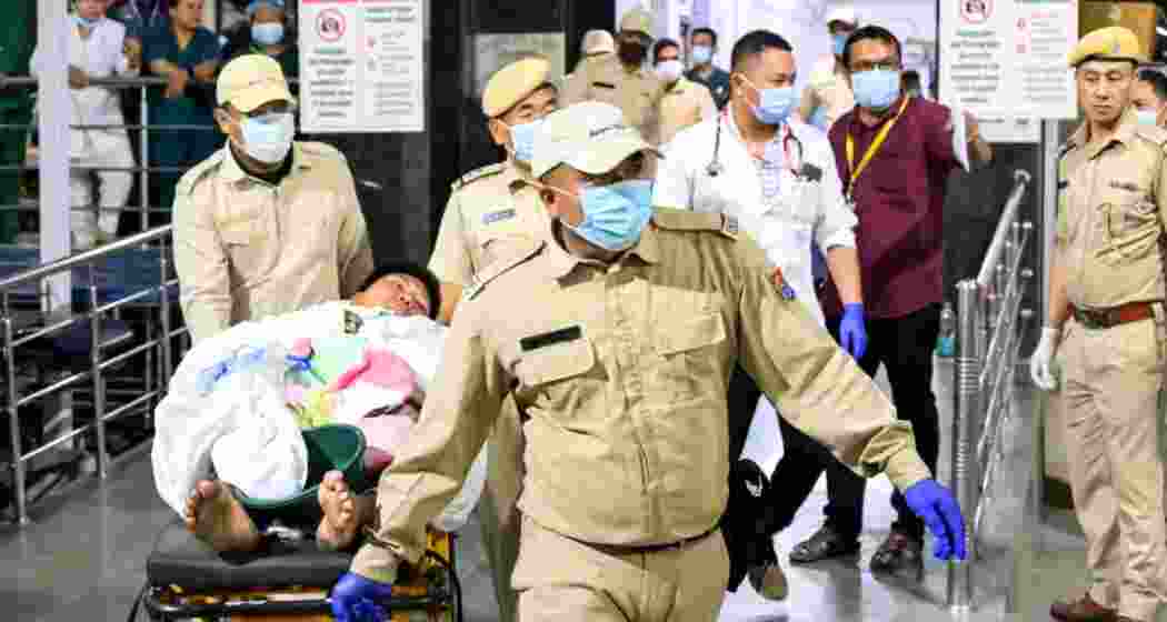 Security pesonnel wheel a patient on a stretcher during the transfer of three Kuki youths from the Regional Institute of Medical Sciences (RIMS), in Imphal, Manipur, on Wednesday, Security pesonnel wheel a patient on a stretcher during the transfer of three Kuki youths from the Regional Institute of Medical Sciences (RIMS), in Imphal, Manipur, on Wednesday,