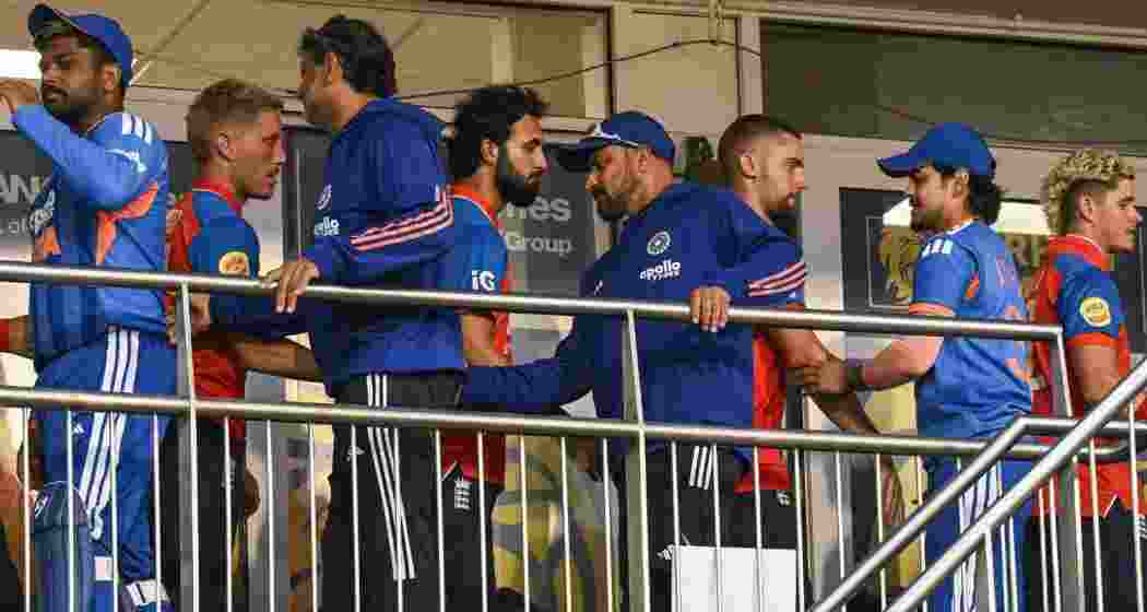 India and England players shake hands as they move between dressing rooms after their first T20I match was abandoned due to rain. India and England players shake hands as they move between dressing rooms after their first T20I match was abandoned due to rain.